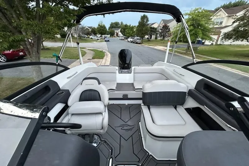 Slide: The Image of 2019 Rinker Q3 OB boat interior with seating, parked on a suburban street. - 6