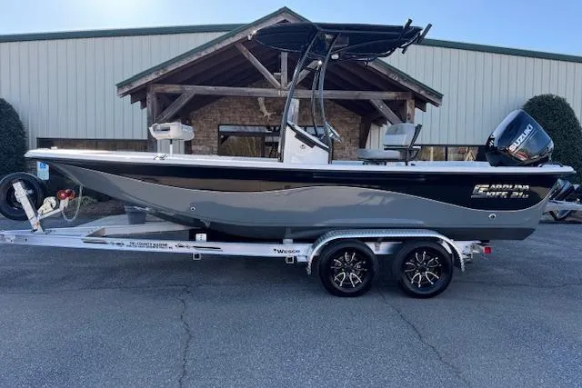 The Image of 2026 Carolina Skiff 21 LS boat on trailer, parked outside a building. - 1