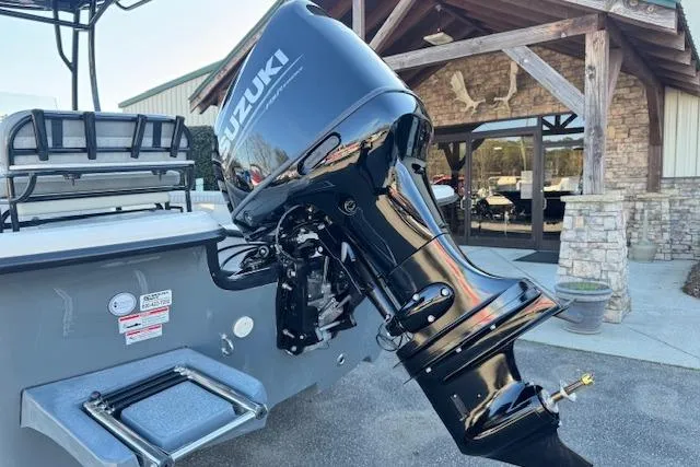 Slide: The Image of 2026 Carolina Skiff 21 LS boat with Suzuki outboard motor, parked near rustic building. - 6