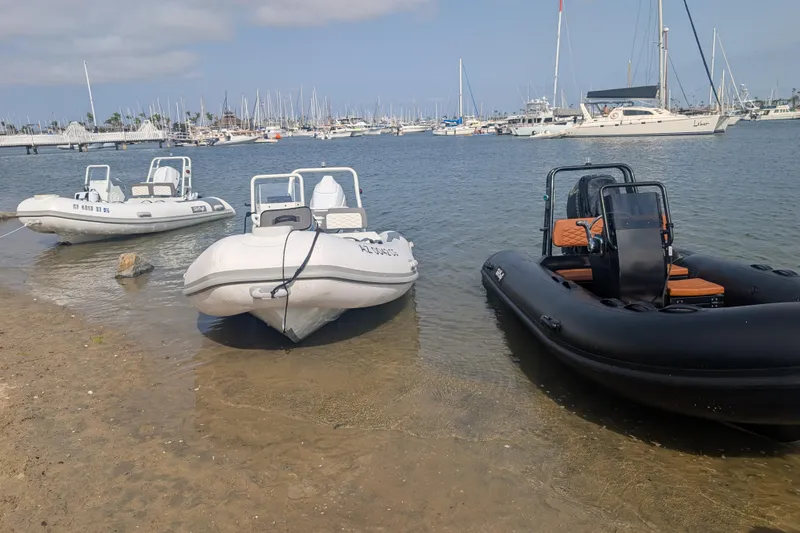Slide: The Image of Three inflatable boats on a sandy shore with marina background. - 11
