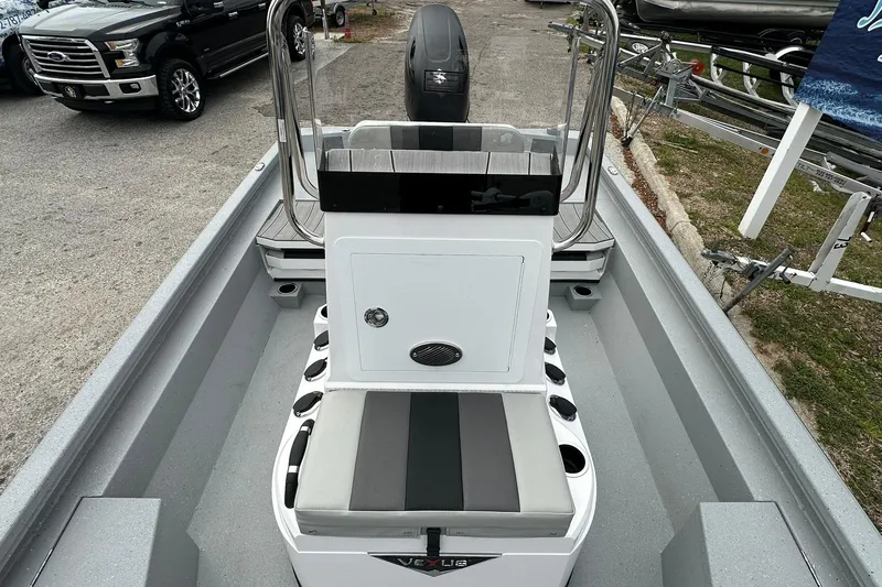 Slide: The Image of 2026 Vexus Defender 201 boat interior with seating and console, parked outdoors. - 14