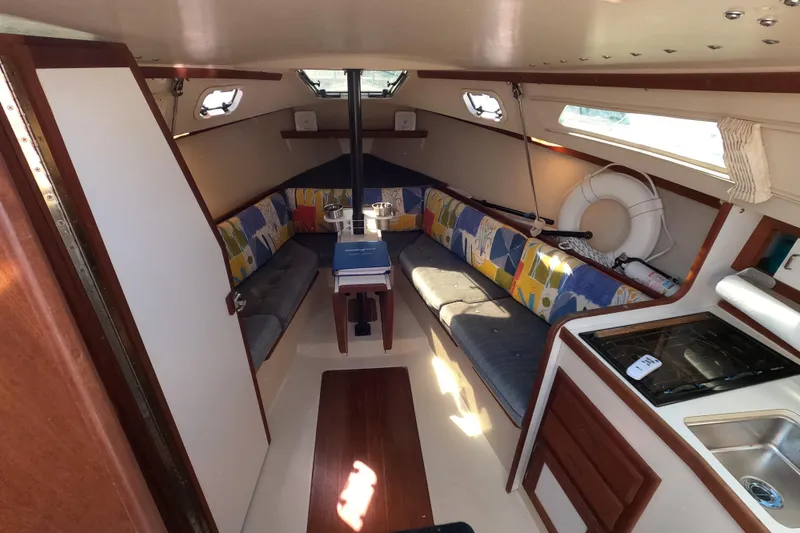 Slide: The Image of Interior of a 1990 Catalina Capri 26 sailboat with colorful seating and compact kitchen area. - 11