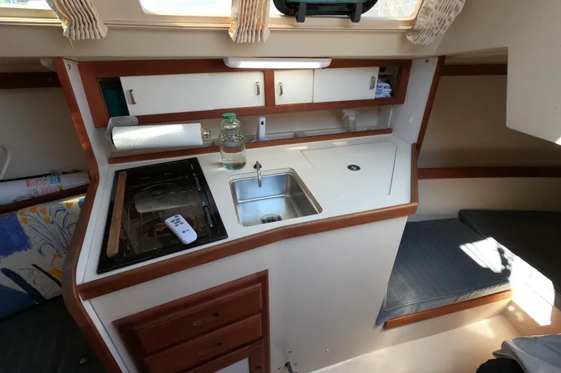 Slide: The Image of 1990 Catalina Capri 26 interior galley with sink, stove, and storage cabinets. - 12