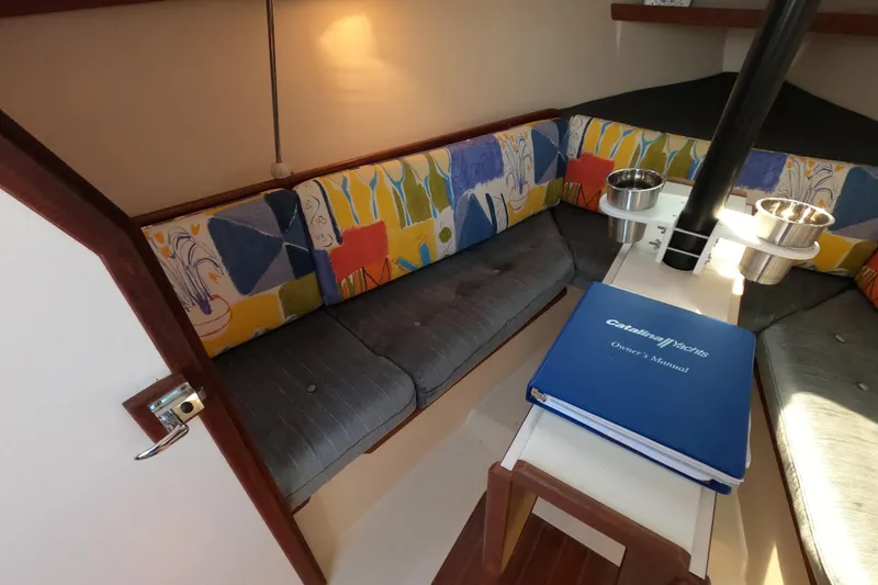 Slide: The Image of Cozy interior of 1990 Catalina Capri 26 sailboat with colorful seating and owner's manual. - 16