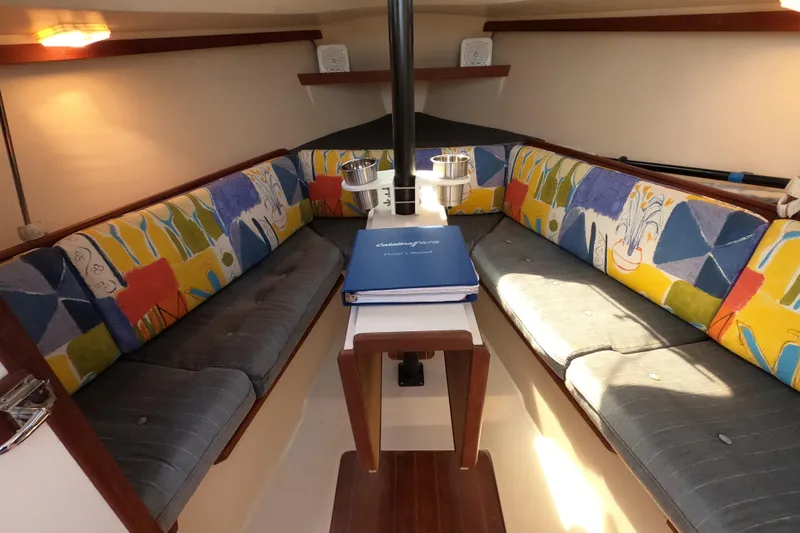 Slide: The Image of Interior of 1990 Catalina Capri 26 sailboat with colorful seating and manual on table. - 18