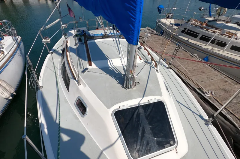Slide: The Image of 1990 Catalina Capri 26 sailboat docked at marina, featuring blue sail and deck view. - 9