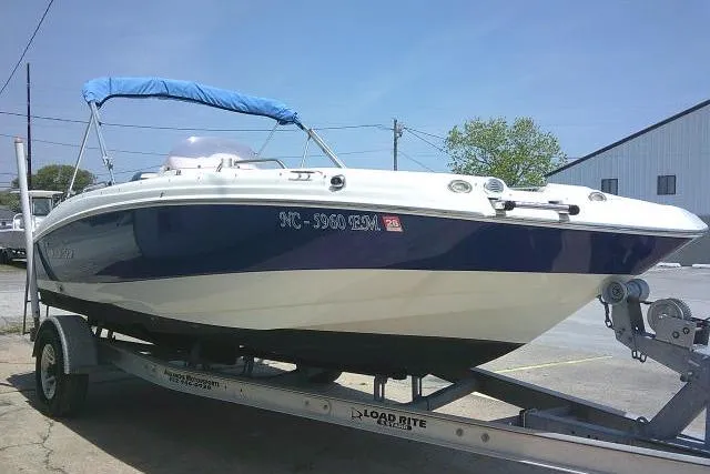 Slide: The Image of 2018 NauticStar 193 SC Deck boat on trailer with blue canopy in outdoor setting. - 12
