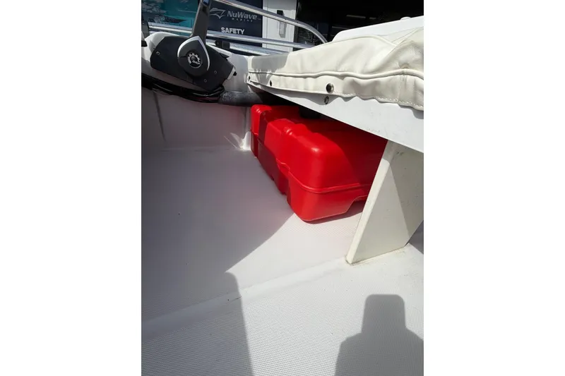 Slide: The Image of 2004 Boston Whaler 150 Sport interior with red storage container and steering wheel. - 11