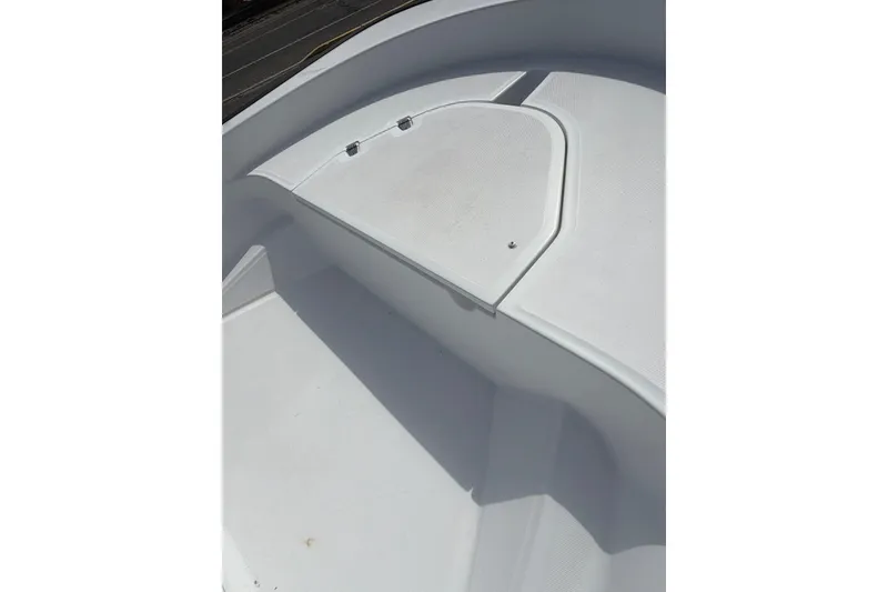 Slide: The Image of 2004 Boston Whaler 150 Sport boat deck, featuring clean white surface and storage compartment. - 12