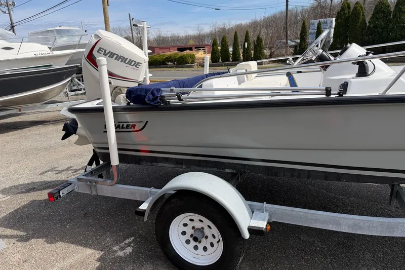 Slide: The Image of 2004 Boston Whaler 150 Sport boat on trailer with Evinrude motor, parked outdoors. - 3