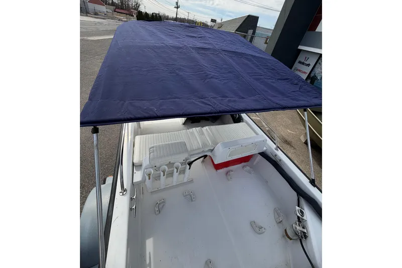 Slide: The Image of 2004 Boston Whaler 150 Sport boat interior with blue canopy and seating. - 5