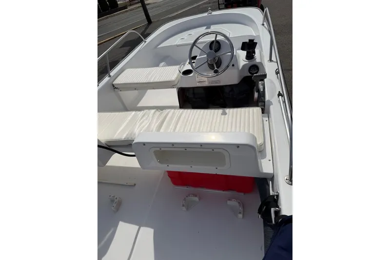 Slide: The Image of 2004 Boston Whaler 150 Sport boat interior with steering wheel and seating. - 8