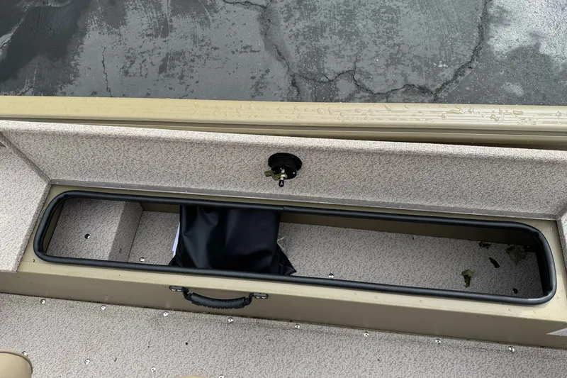 Slide: The Image of 2026 Lund 2075 Alaskan SS boat storage compartment with black bag, wet surface. - 18