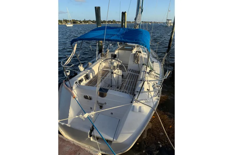 Slide: The Image of 1990 Beneteau First 32s5 sailboat docked with blue canopy, calm waters in background. - 12