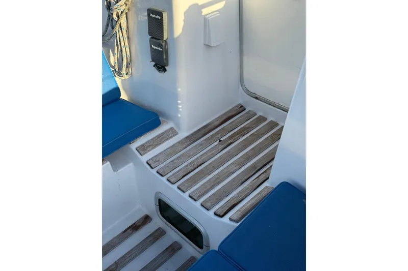 Slide: The Image of Cockpit of 1990 Beneteau First 32s5 sailboat with wooden flooring and blue cushions. - 13