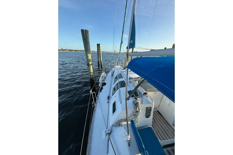 Slide: The Image of 1990 Beneteau First 32s5 sailboat docked, featuring blue canopy and clear skies. - 19