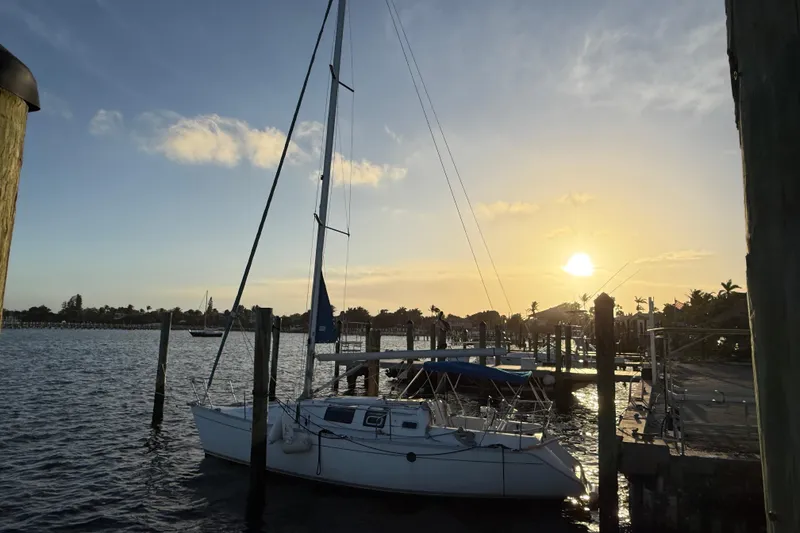 Slide: The Image of Sailboat Beneteau First 32s5, 1990 model, docked at sunset with scenic waterfront view. - 2