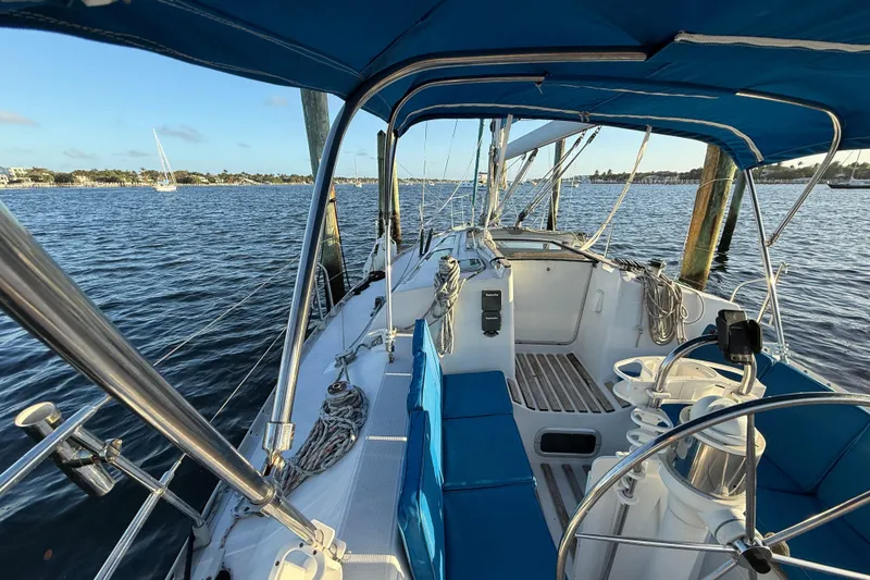 Slide: The Image of 1990 Beneteau First 32s5 sailboat cockpit with blue canopy, docked on calm waters. - 20