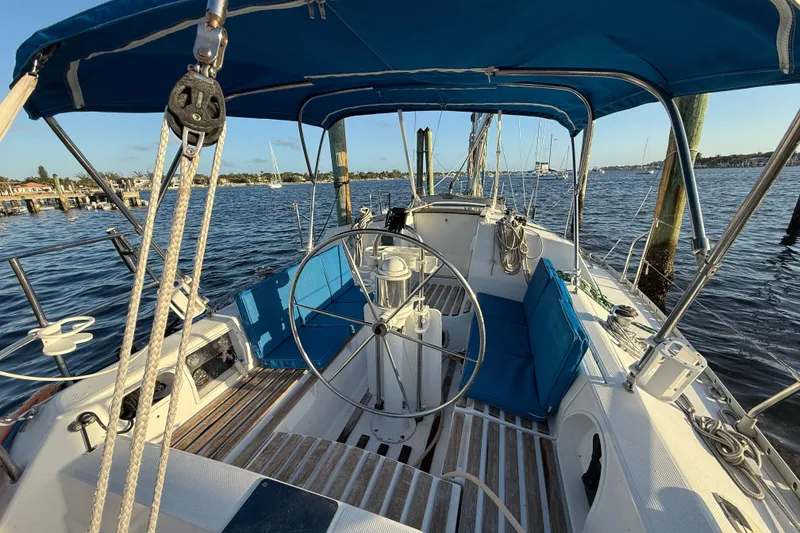 Slide: The Image of 1990 Beneteau First 32s5 sailboat cockpit with blue cushions and steering wheel. - 21