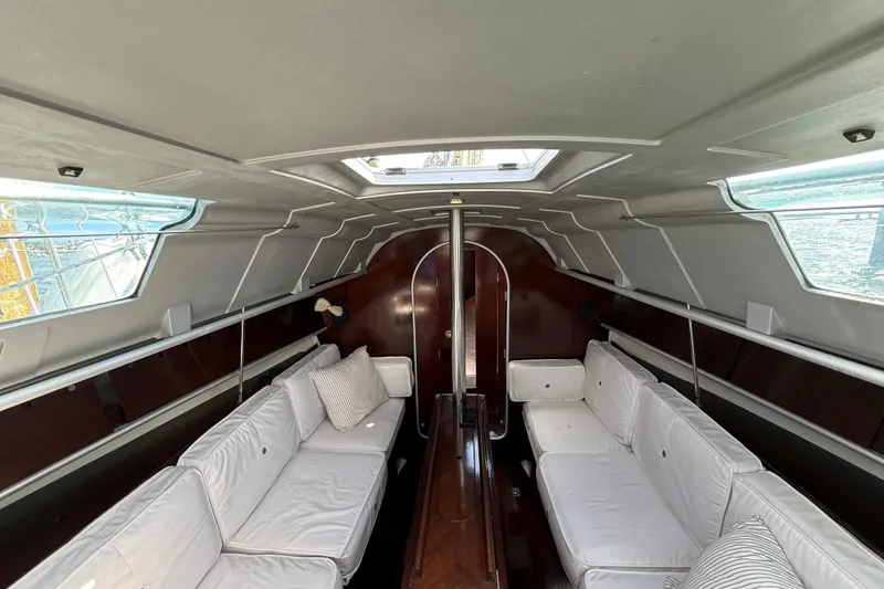 Slide: The Image of Interior of a 1990 Beneteau First 32s5 sailboat with white seating and wood accents. - 26