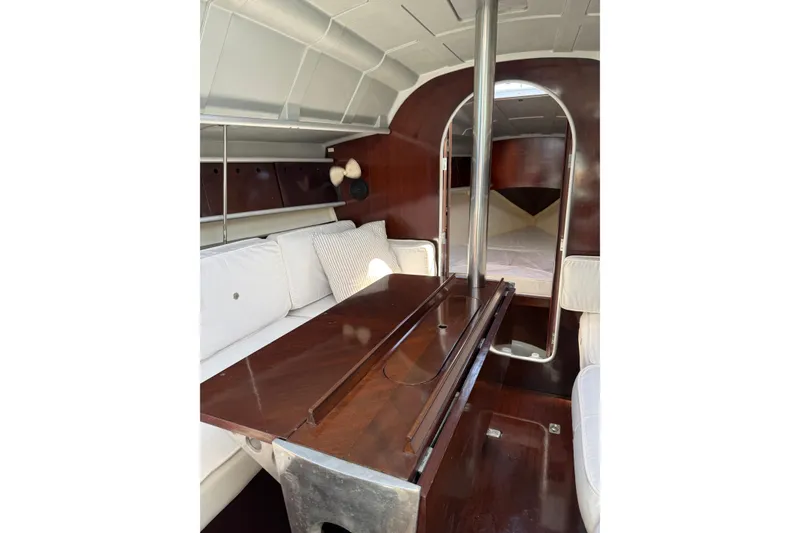 Slide: The Image of Interior of 1990 Beneteau First 32s5 sailboat with wooden table and white seating. - 38