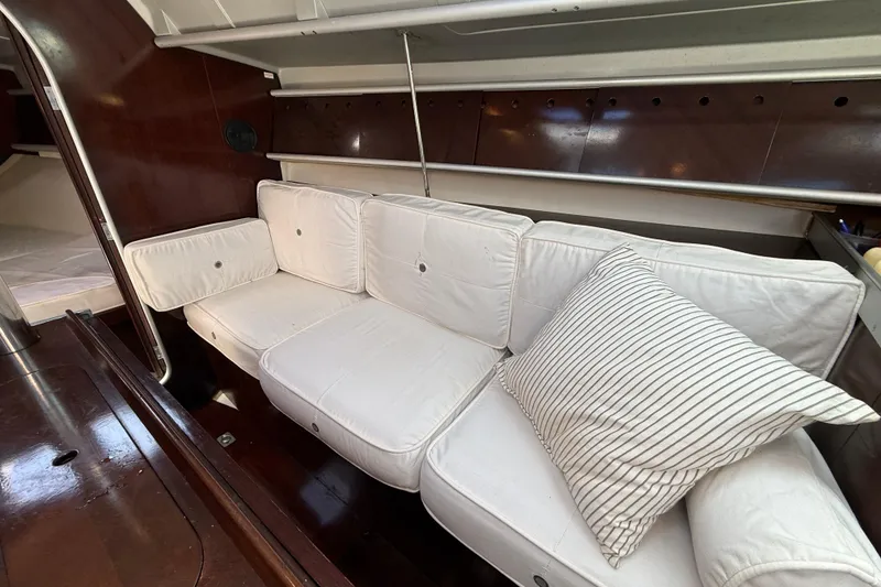 Slide: The Image of Interior of 1990 Beneteau First 32s5 yacht with white cushioned seating. - 42