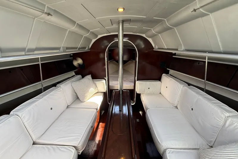 Slide: The Image of Interior of 1990 Beneteau First 32s5 yacht with white seating and wooden accents. - 43