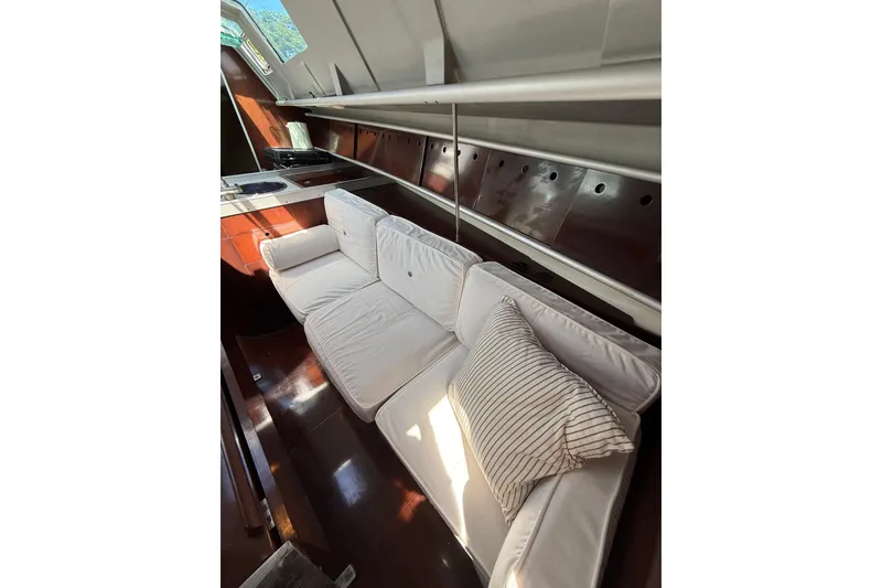 Slide: The Image of Interior of 1990 Beneteau First 32s5 yacht with white cushioned seating and striped pillow. - 44
