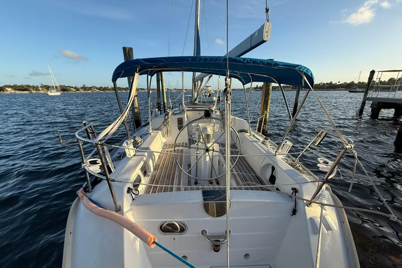 Slide: The Image of 1990 Beneteau First 32s5 sailboat docked, featuring a spacious cockpit and blue canopy. - 6