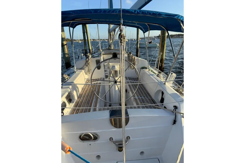 Slide: The Image of 1990 Beneteau First 32s5 sailboat cockpit with blue canopy, docked on calm water. - 8