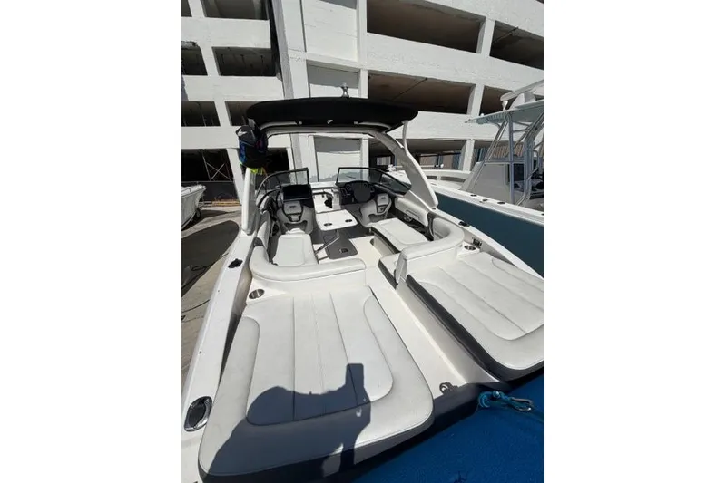 Slide: The Image of 2013 Chaparral 277 SSX boat interior with seating and helm, docked near a building. - 4