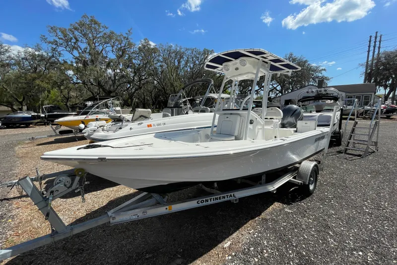 The Image of 2023 Sea Pro 208 Bay boat on trailer, parked outdoors under a clear blue sky. - 1