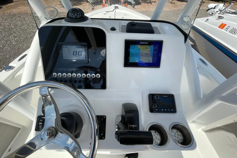 Slide: The Image of 2023 Sea Pro 208 Bay boat dashboard with steering wheel, controls, and navigation screens. - 12