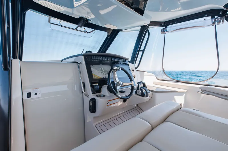 Slide: The Image of 2021 Boston Whaler 350 Realm dashboard with navigation display and controls, overlooking the ocean. - 23