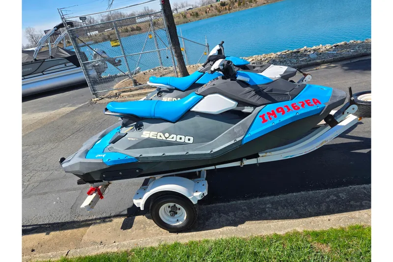 The Image of 2017 Sea-Doo Spark 2up jet skis on trailer by a lake. - 0