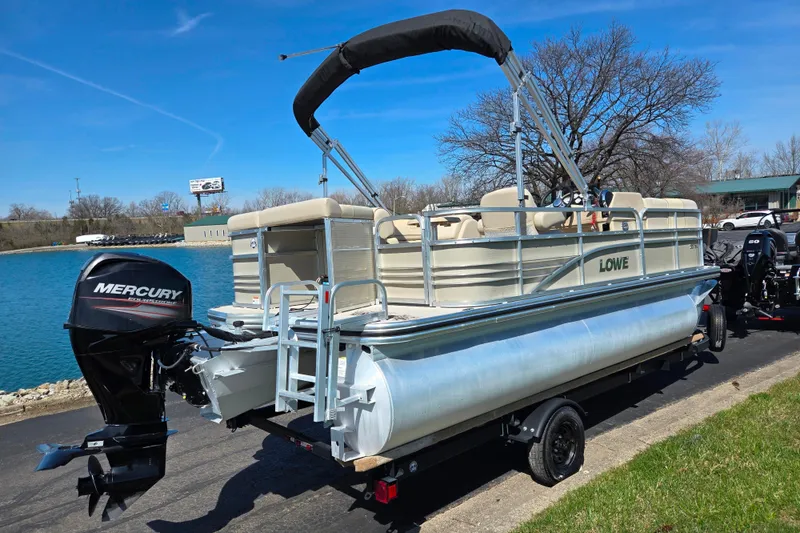 Slide: The Image of 2016 Lowe SS 190 pontoon boat with Mercury outboard motor on trailer by a lake. - 1