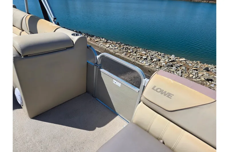 Slide: The Image of Interior of a 2016 Lowe SS 190 boat with beige seating by a lake. - 11