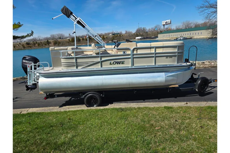 Slide: The Image of 2016 Lowe SS 190 pontoon boat on trailer by a lake. - 9