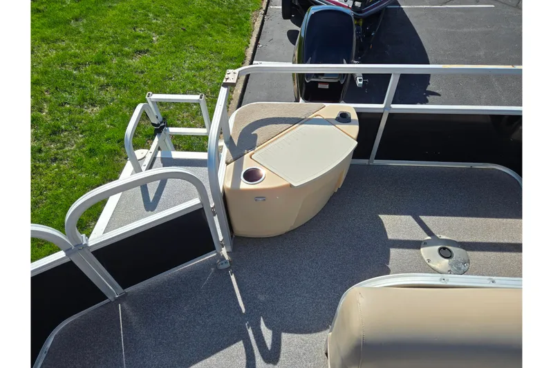 Slide: The Image of 2016 Sun Tracker Bass Buggy 18 DLX pontoon boat with seating and railing, parked on grass. - 18
