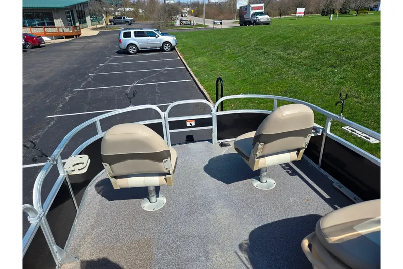 Slide: The Image of 2016 Sun Tracker Bass Buggy 18 DLX pontoon boat with seating, parked in a lot. - 25