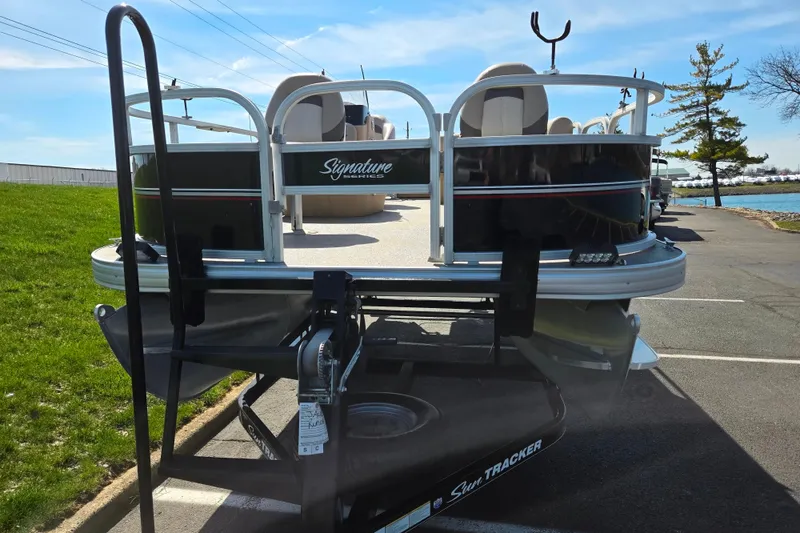 Slide: The Image of 2016 Sun Tracker Bass Buggy 18 DLX pontoon boat on trailer, parked near water. - 6