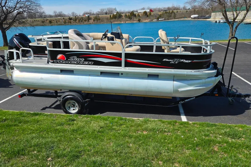 Slide: The Image of 2016 Sun Tracker Bass Buggy 18 DLX pontoon boat on trailer by a lake. - 9