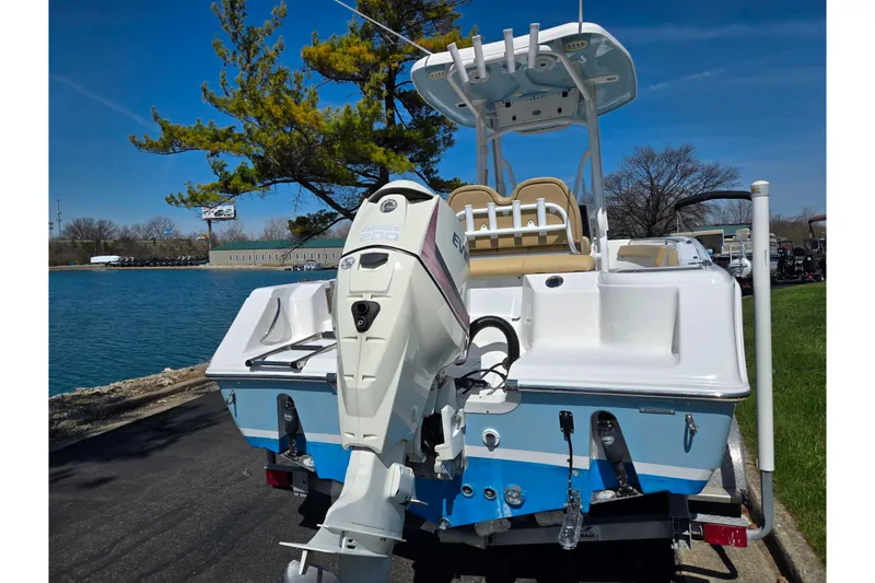 Slide: The Image of 2016 Tidewater 220 LXF boat with Evinrude engine, docked by a serene lake. - 2