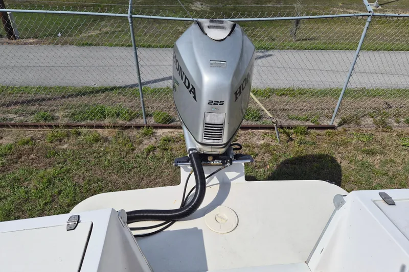 Slide: The Image of 2002 Mako 221 Center Console with Honda 225 outboard motor, parked near chain-link fence. - 5