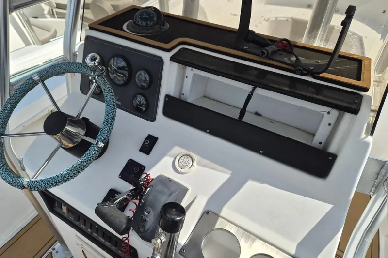 Slide: The Image of Center console of a 2002 Mako 221 boat with steering wheel and gauges. - 8
