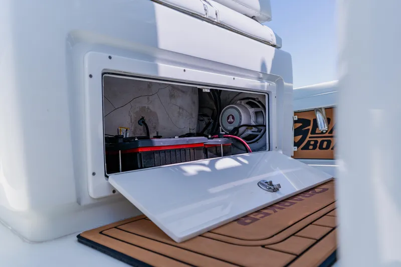 Slide: The Image of Open storage compartment on 2017 Barker Boatworks 26, revealing battery and wiring. - 27