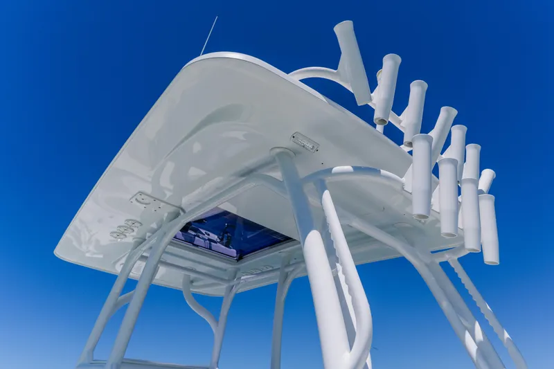 Slide: The Image of 2017 Barker Boatworks 26 T-top with rod holders against clear blue sky. - 33