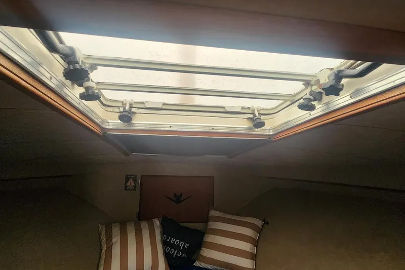 Slide: The Image of Interior view of 1985 Bertram 33 Flybridge Cruiser cabin with skylight and striped pillows. - 17