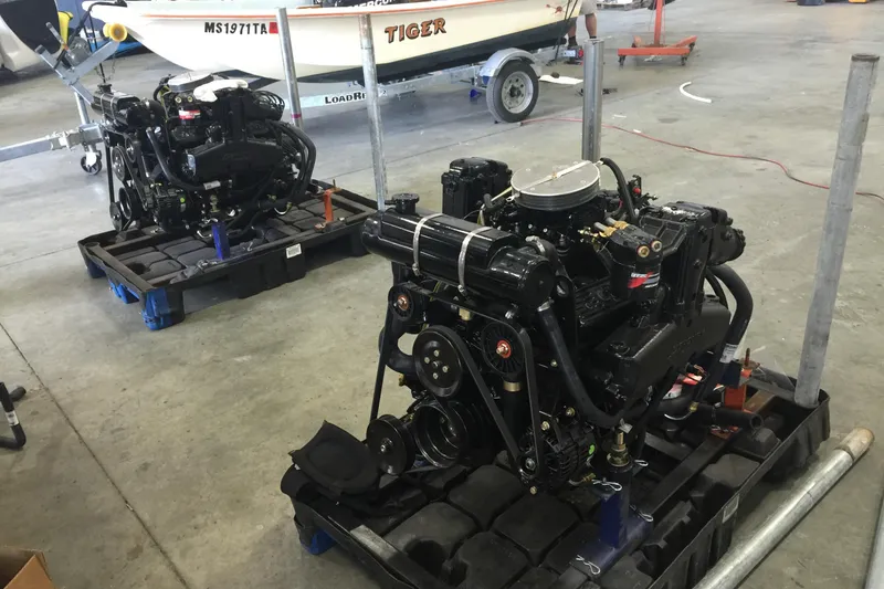 Slide: The Image of Two marine engines on pallets in a workshop, near a boat trailer. - 28
