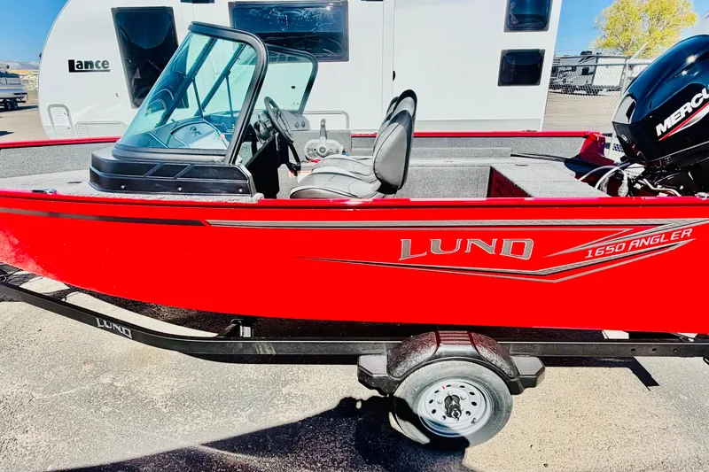 Slide: The Image of Red 2026 Lund 1650 Angler Sport boat with Mercury engine, parked on trailer. - 2